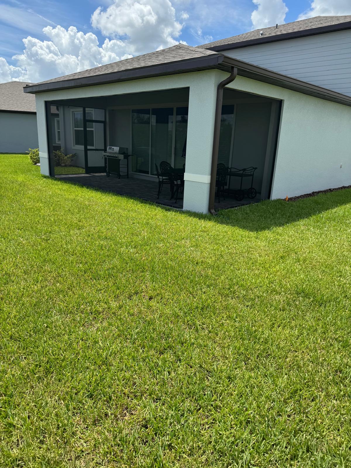 Screened lanai under covered patio with green lawn in Florida