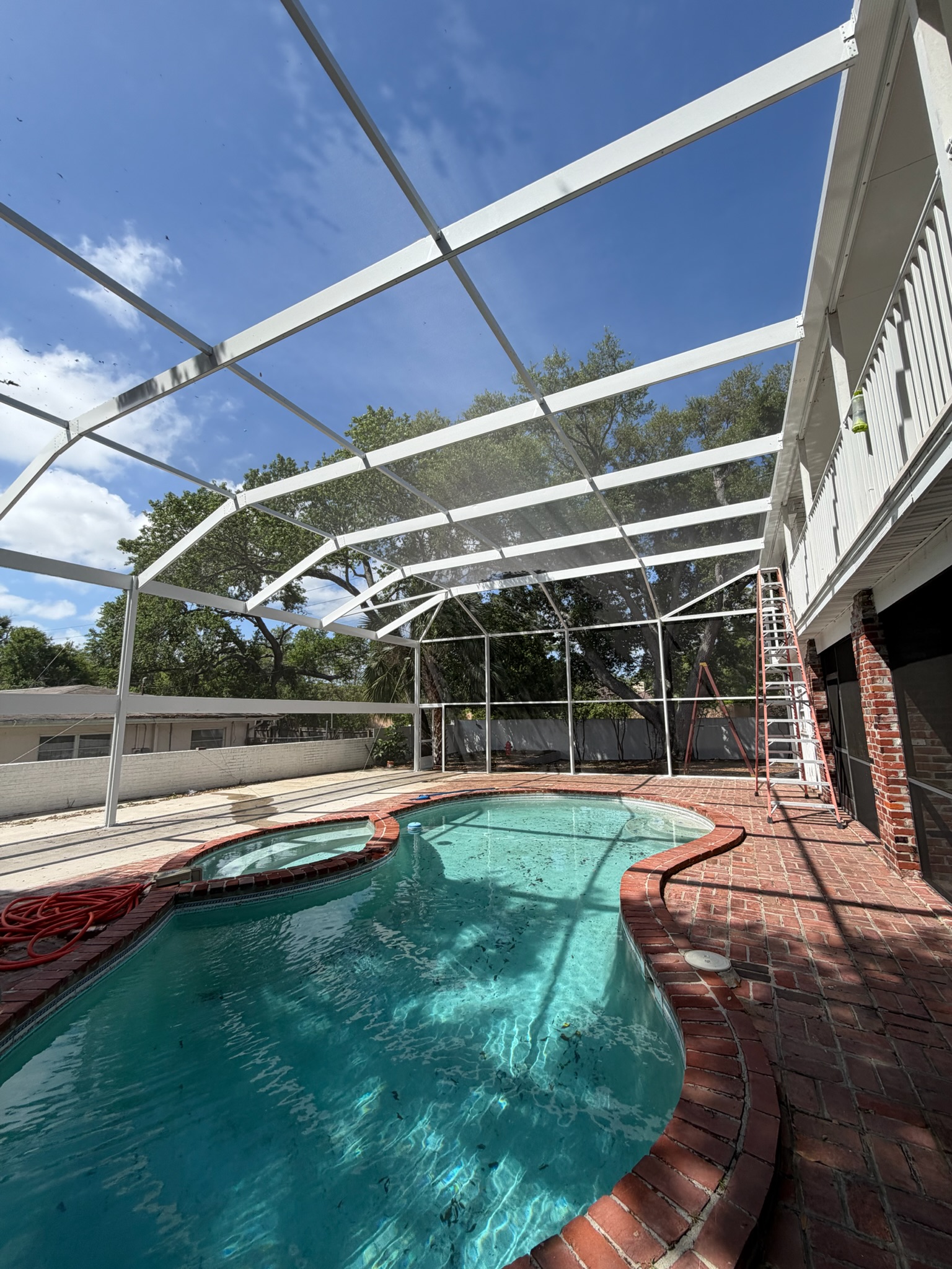 White aluminum pool enclosure over a brick-paved pool, Tampa Bay, Florida